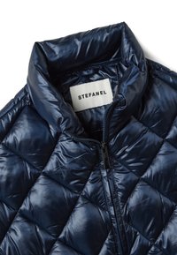 Marineblaue gesteppte Jacke mit hohem Kragen, Frontreißverschluss und "STEFANEL" Markenlabel innen am Kragen.