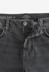 Tummanharmaat slim fit -farkut, joissa on vetoketjulla toimiva yksityiskohta, metallinappikiinnitys ja hillitty tekstuuri. Mukana etutaskut ja brändätty vyötärö.