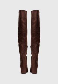 Καφέ χρήσιμες μπότες πάνω από το γόνατο, φτιαγμένες από μαλακό ύφασμα, με κομψό σχέδιο, τετράγωνες γόβες και πλαϊνές φερμουάρ. Λείος υφή με ματ φινίρισμα.