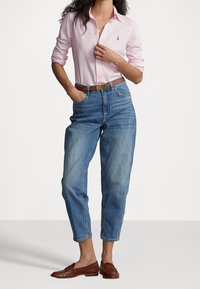 Ljusrosa skjorta med knappar, blå high-waisted jeans, brunt läderbälte och bruna flätade loafers. Avslappnad, figursydd design med lös passform.