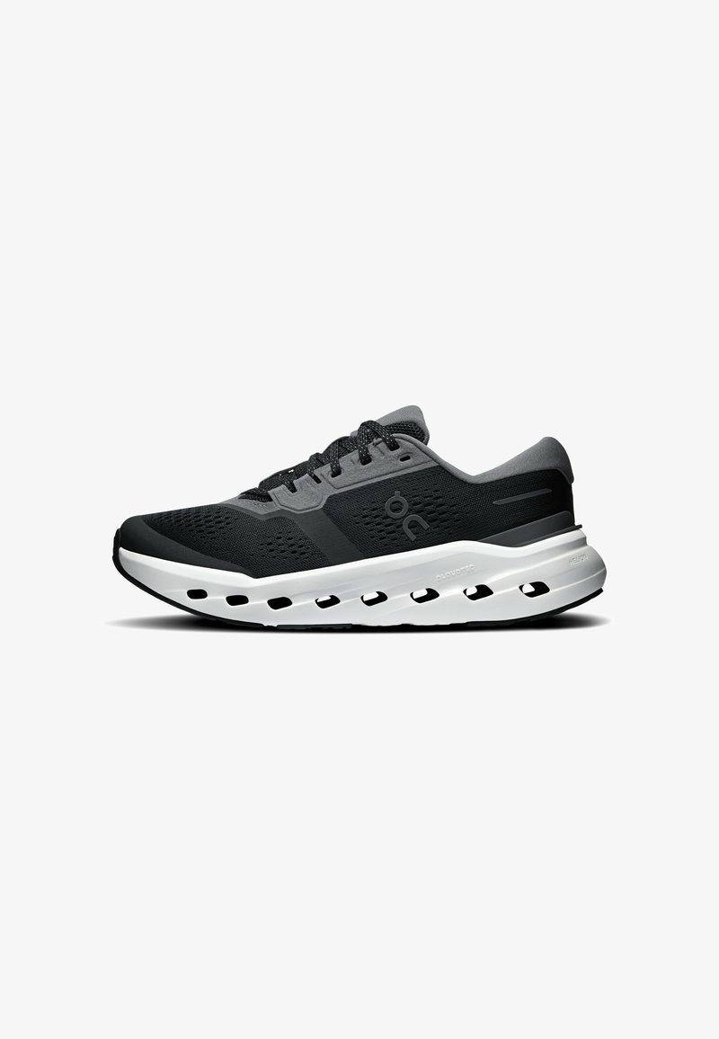 Chaussure de course athlétique noire et grise avec semelle blanche, dotée de plusieurs trous de ventilation latéraux et de lacets noirs.