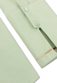 Lichtgroen shirt met knoopsluiting, voorzien van contrasterende borduursels in goud, rood en beige langs de zoom en een splitdetail bij de mouw.