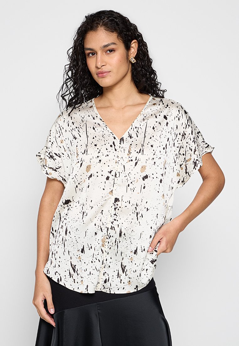 Witte blouse met korte mouwen en een zwart en gouden spettern patroon. Zacht materiaal met een ontspannen pasvorm en V-hals. Lichtgewicht en ademend.