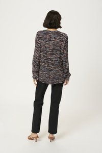 Long-sleeve, flowy top in navy with multicolored wave pattern; paired with black fitted pants and beige heeled sandals. Soft texture.