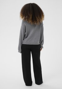 Jersey gris con mangas ampias, tejido texturizado, costura de hombro caída, combinado con pantalones de pierna ancha negros, tela suave, corte amplio.