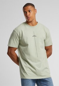 Light green short-sleeve t-shirt made of soft cotton, featuring a centered black text print reading "THINK DIFFERENT." in a minimalist style.