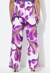 Pantalones de pierna ancha con estampado floral que presentan un fondo blanco con grandes patrones de flores moradas y rosas, cinturilla elástica y un ajuste relajado.
