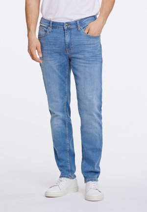 Hellblaue Denim-Jeans mit gerader Passform, fünf Taschen und Reißverschluss. Getragen mit weißen Sneakern, die dezente Waschungen im Stoff aufweisen.