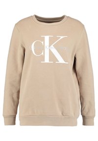 Felpa beige in morbido cotone con maniche lunghe. Caratterizzata da un grande logo bianco "CK" e il testo "Calvin Klein Jeans" sul davanti.