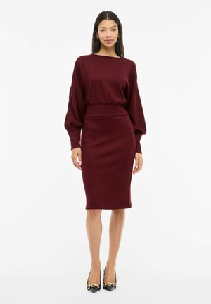 Robe en maille bordeaux avec des manches longues bouffantes et une jupe crayon ajustée. Présente une texture côtelée et une ceinture assortie.