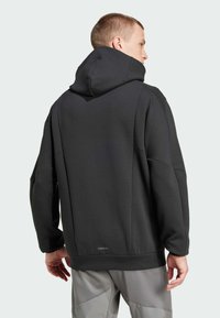 Sweatshirt à capuche noir avec une coupe décontractée, fabriqué en tissu doux. Présente une poche kangourou, des poignets côtelés et un logo discret sur l'ourlet.