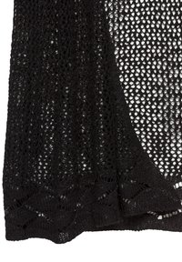 Shawls neri a maglia aperta con un motivo testurizzato e un bordo ondulato. Il materiale è leggero e traspirante, ideale da sovrapporre.