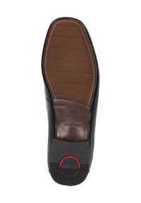 Schwarzlederner Schuhsohle mit strukturiertem braunem Gummi-Griff, versehen mit einem runden roten Akzent und eingestanztem Markennamen. Flaches, elegantes Design.