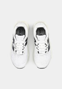 White athletic shoes with a textured upper, mesh detailing, black accents, lightweight design, and traditional lacing system.