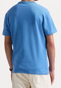 Camiseta de algodón de color azul claro y manga corta. Diseño de cuello redondo con una textura suave, con costuras a lo largo de las mangas y el dobladillo.