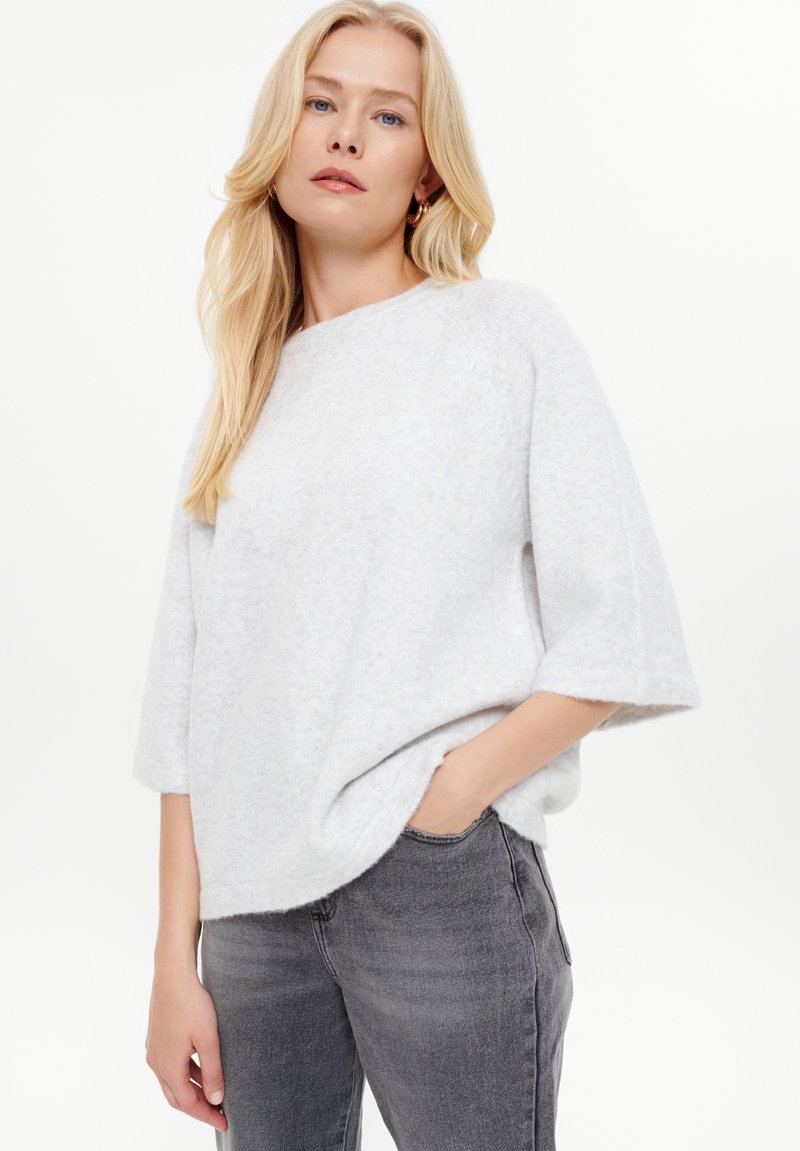 Maglione oversize grigio chiaro con maniche corte, realizzato in tessuto morbido. Presenta un colletto rotondo e una vestibilità rilassata. Finitura testurizzata.