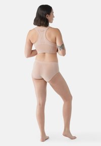 Reggiseno sportivo rosa chiaro e slip coordinato realizzati in un tessuto morbido e elastico. Presentano un design con schiena a racer e dettagli di cucitura minimalisti.