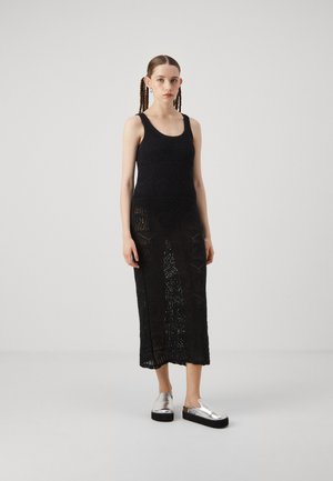 Rochie midi neagră din croșetat cu un model texturat, având un decolteu rotunjit. Asortată cu pantofi slip-on cu platformă argintii.