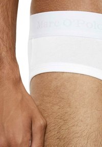 Weiße Baumwoll-Boxershorts mit glatter Textur, ausgestattet mit einem dezent geprägten Logo am Bund und einer engen Passform um den Oberschenkel.