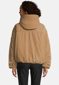 Tan pufferjack met een oversized capuchon, elastische manchetten en een gathered zoom. Gladde textuur, eenvoudig ontwerp en geen zichtbare patronen of hardware.