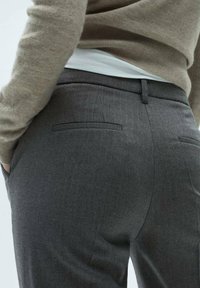 Pantalons gris ajustés en tissu texturé, avec deux poches arrière et une coupe slim. La taille est plate avec une passant de ceinture.