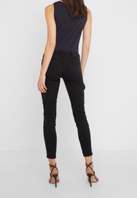 Svarta skinny jeans med hög midja och sidfickor. Matchas med svarta sandaletter med remmar. Slät denimtextur.