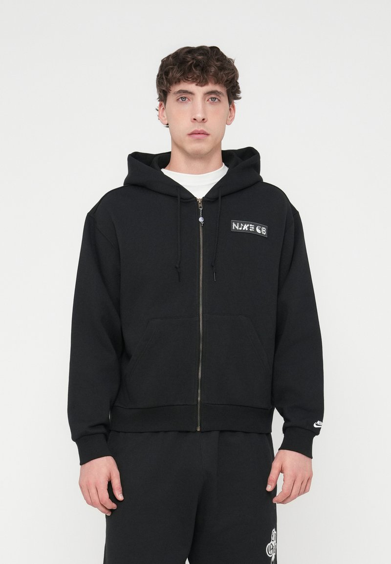 Μαύρο φούτερ με φερμουάρ, κατασκευασμένο από βαμβακερό μείγμα, με τσέπη καγκουρό, λογότυπο στο στήθος και κουκούλα με κορδόνι.