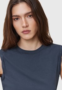Navy blue sleeveless top with a smooth texture and gathered detailing on the shoulders. Round neckline, casual fit, made from lightweight fabric.