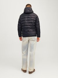 Tamsiai mėlynas pūkinis džinsas su gobtuvu, su siuvinėtomis panelėmis; derinamas su šviesiai plačiais, išplėšytais džinsais ir ruda avalyne.