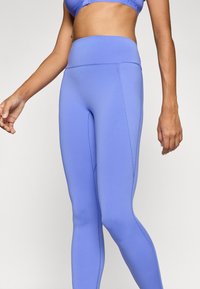 Μωβ κολάν ψηλόμεσο κατασκευασμένο από ελαστικό υλικό με ραφές flatlock για άνεση και κομψό σχέδιο. Διαθέτει λεία υφή.