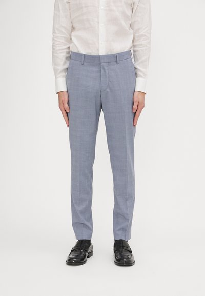 Pantaloni su misura azzurri realizzati in tessuto intrecciato, con una texture liscia, tasche frontali e un design slim fit. Abbinati a scarpe nere.