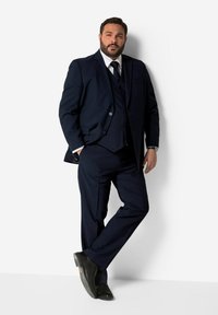 Abito tre pezzi blu navy con revers a punta, camicia da dress coordinata e scarpe nere. Presenta un tessuto liscio e una vestibilità su misura.