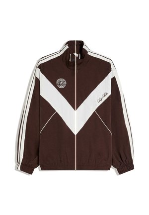 Jachetă sport maro și albă cu fermoar, model în formă de chevron alb, logo pe pieptul stâng și inscripția „Stay Late” pe pieptul drept.