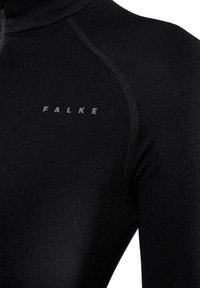 Haut thermique noir avec un col montant, un design sans couture et des accents texturés, avec le nom de la marque "FALKE" imprimé en gris sur la poitrine.