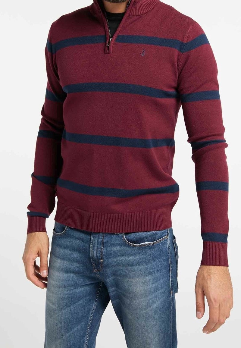 Burgundowy sweter na zamek błyskawiczny z granatowymi paskami, z prążkowanymi mankietami i dołem, wykonany z miękkiego dzianinowego materiału. Ma małe logo na klatce piersiowej.