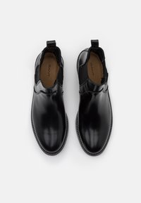 Czarne skórzane botki za kostkę z elastycznymi bocznymi panelami, zaokrąglonym noskiem i pętelką z tyłu; gładkie wykończenie i kontrastowe przeszycia.