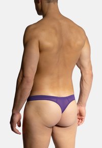 Lila Tangahöschen mit glatter Textur und minimalistischem Design, das einen niedrig sitzenden Bund und eine konturierte Rückseite zeigt.