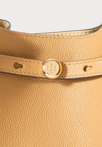 Τσάντα ώμου από καφέ δέρμα με υφή, με χρυσό κυκλικό κουμπί και ραμμένη ταινία για κλείσιμο.