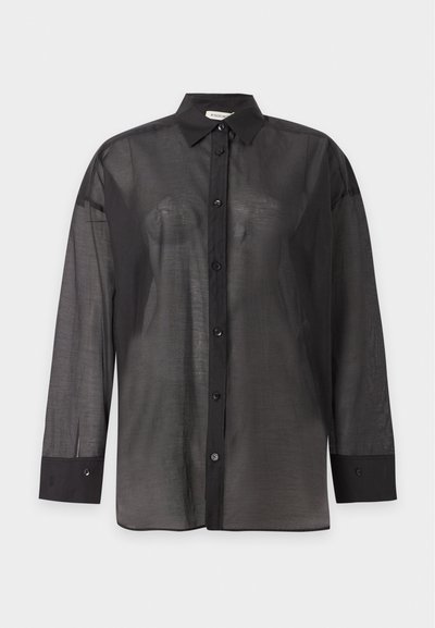 Chemise noire transparente à manches longues, boutonnée, avec col standard et poignets boutonnés, présentée sur un fond clair uni.