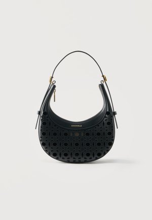 Black crescent-shaped leather handbag with circular cutouts, gold logo "COCCINELLE," single handle, and zipper closures on each side.