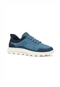Blaue Sportschuhe mit strukturiertem Mesh-Obermaterial, dunkelblauen Akzenten, Schnürdesign und einer dicken weißen Sohle mit wellenförmigen Linien.