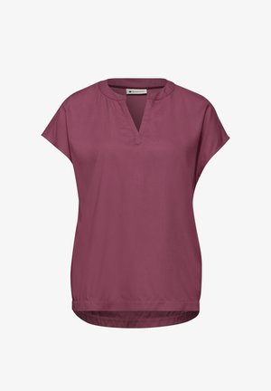 Volná halenka s krátkými rukávy ve fialové barvě s kulatým výstřihem a V-obloukovým zářezem na předním lemu, který je mírně zakřivený a vzadu delší.