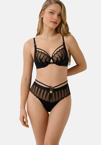 Ensemble de lingerie en dentelle noire comprenant un soutien-gorge structuré avec des panneaux transparents, des bretelles ajustables, et une culotte taille haute assortie avec un accent audacieux.