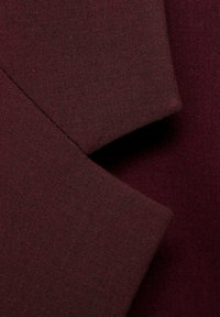 Tissu bordeaux foncé avec un tissage fin et texturé, plié pour afficher des formes rectangulaires superposées aux bords nets.