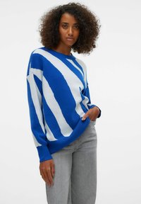 Pull rayé bleu et blanc à coupe ample, avec poignets et ourlet côtelés. Fabriqué en matériau doux, avec un motif ondulé audacieux. Style décontracté.