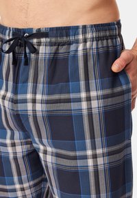 Navy ja vaaleansinisiä ruudullisia pyjamashortseja, joissa on joustava vyötärönyöri ja sivutaskut. Pehmeää puuvillamateriaalia.