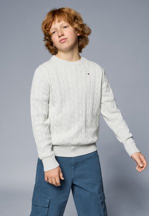 Helles graues, kabelgestricktes Sweatshirt mit gerippten Bündchen und Saum, kombiniert mit blauen Cargo-Hosen mit Seitenentaschen und lässiger Passform.