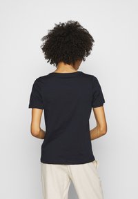 Camiseta de algodón azul marino con manga corta y cuello redondo, textura suave y diseño sencillo. La vista trasera muestra detalles de los hombros y el cuello.