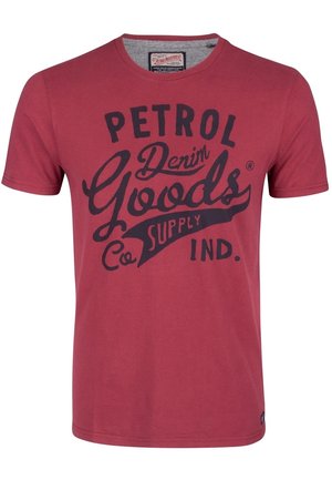 Czerwona koszulka z krótkim rękawem i okrągłym dekoltem, z czarnym napisem "Petrol Denim Goods Co. Supply Ind." na przodzie.