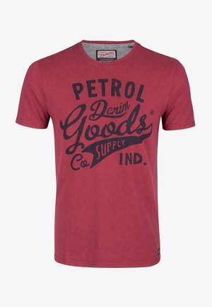 Czerwona koszulka z krótkim rękawem i okrągłym dekoltem, z czarnym napisem "Petrol Denim Goods Co. Supply Ind." na przodzie.